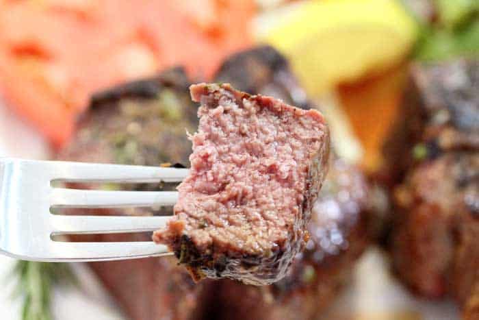 closeup of bite of lamb on fork.