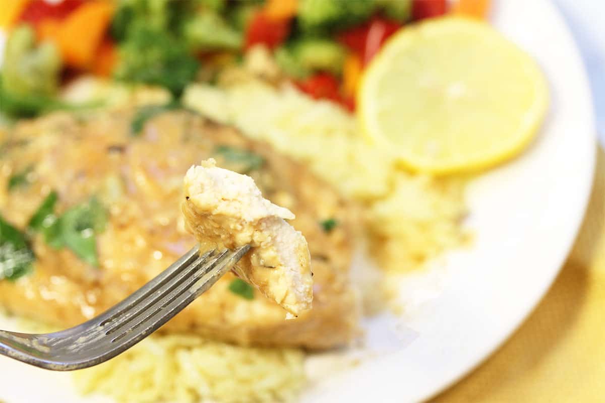 Bite of chicken showing moistness above plated serving.