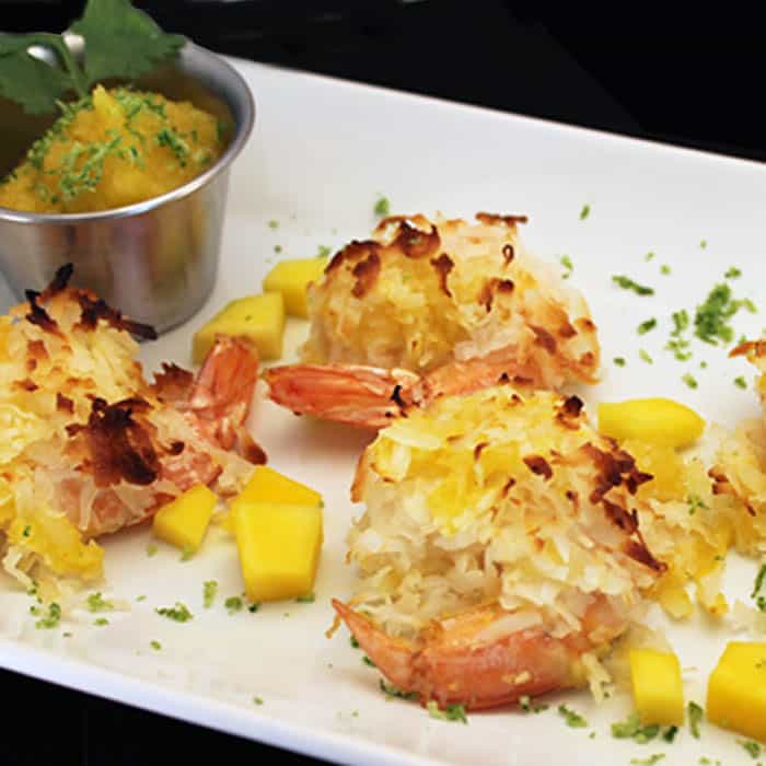 Coconut Shrimp on white plate with a small dish of mango salsa for dipping.