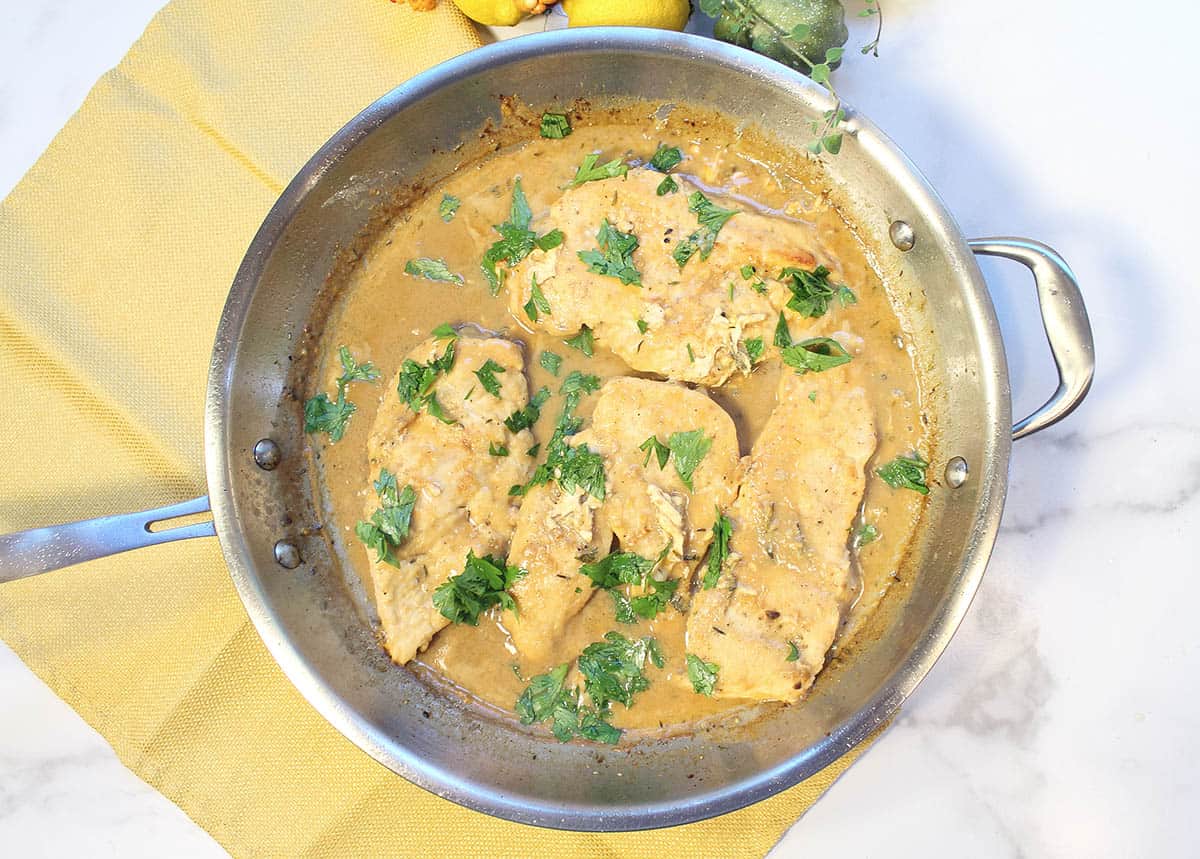 Cooked chicken in skillet with a sprinkle of parsley.