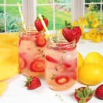 Two Strawberry Lemonades with thyme with strawberry garnish.