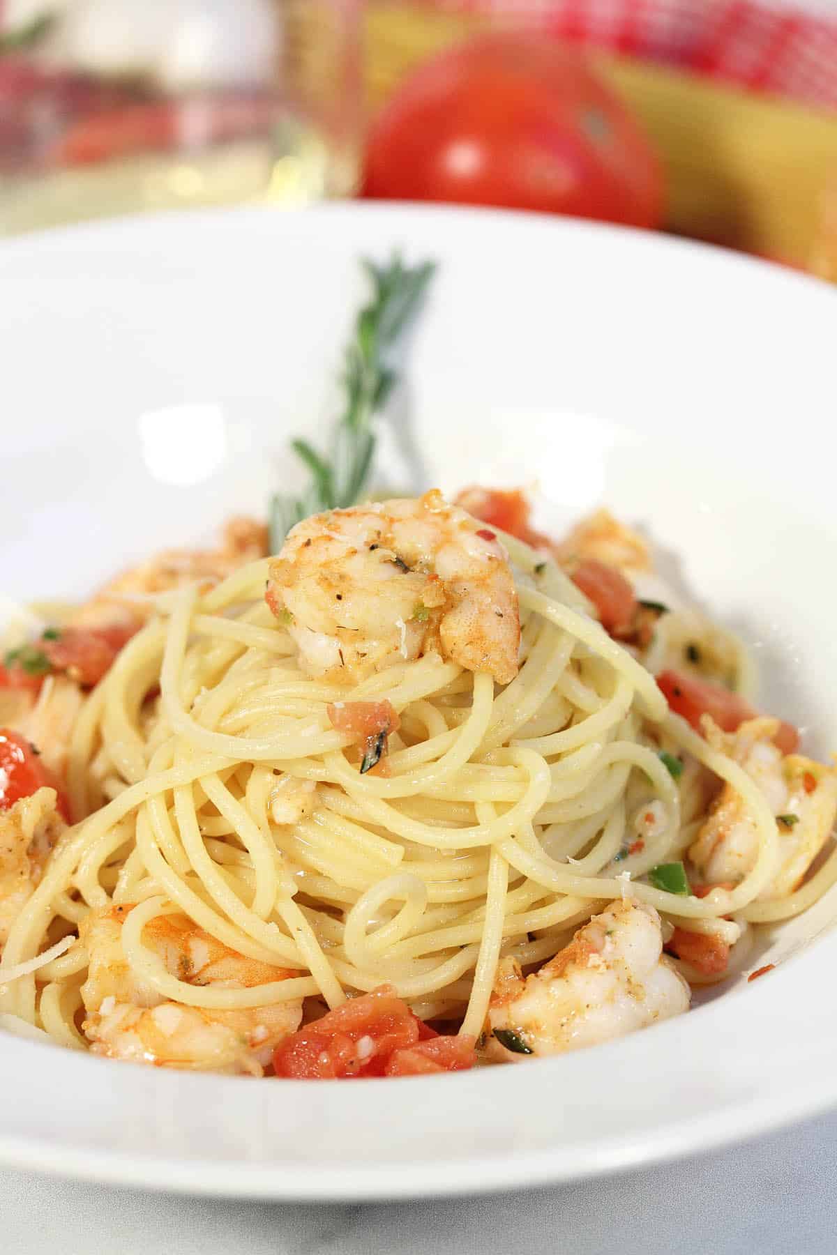 Closeup of pasta in white bowl with rosemary sprig.