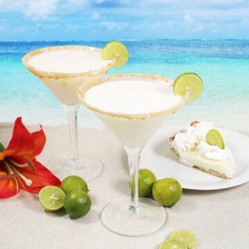 Two key lime pie martinis with lime wheel and graham cracker rim.