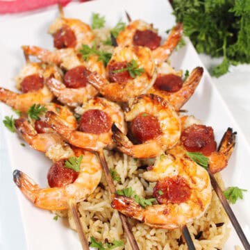 Shrimp and chorizo skewers served on a bed of rice.
