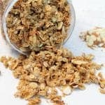 Granola spilling out of container showing crunchy oats and nuts.