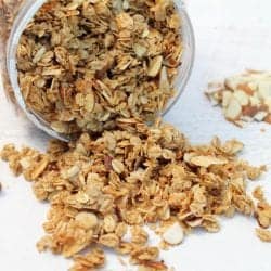 Granola spilling out of container showing crunchy oats and nuts.