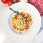 overhead of rattlesnake pasta in white bowl with tomatoes in background.