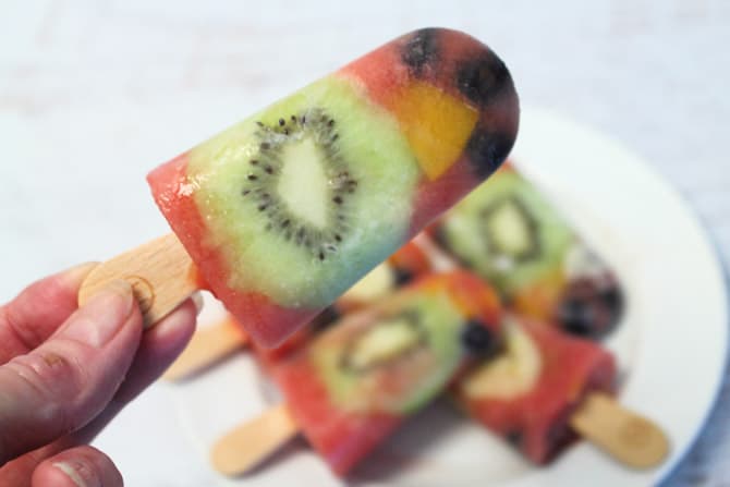 A closeup holding a popsicle over the other popsicles.