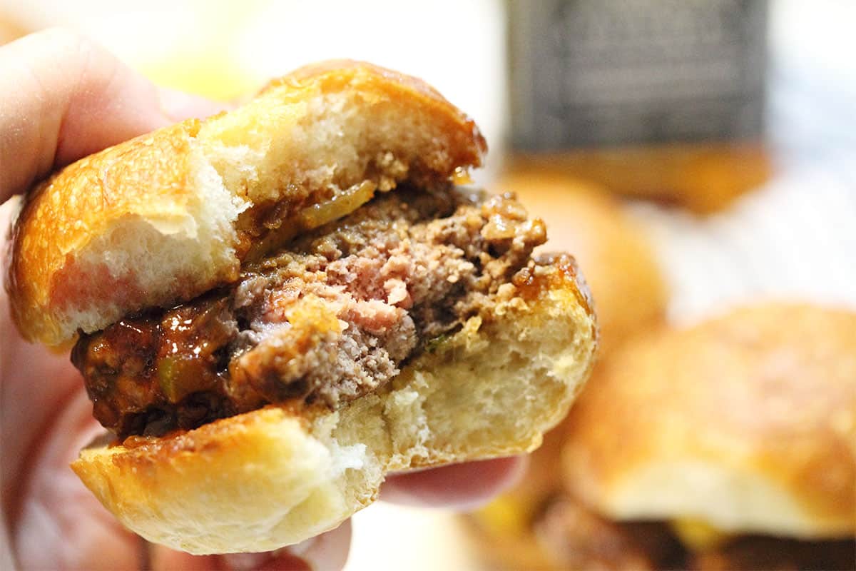 Holding sliders burgers with bite taken out.