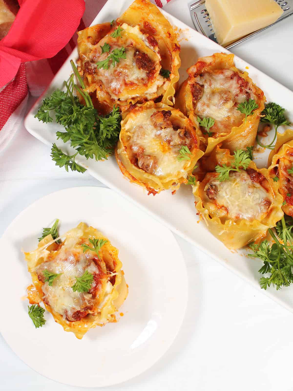 Overhead of lasagna cups on platter and single on plate.