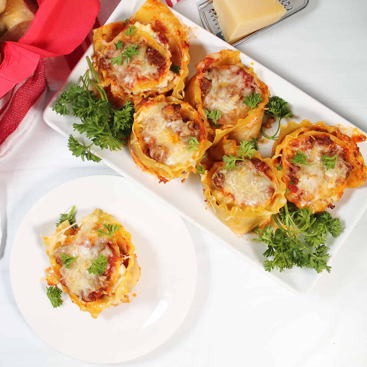 Mini lasagna cups on platter with one serving plated.