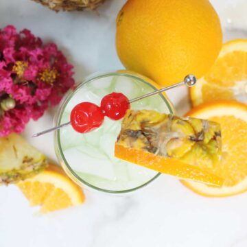 Overhead of single blue long island cocktail with flowers.