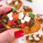 Holding bruschetta with pesto and mozzarella.