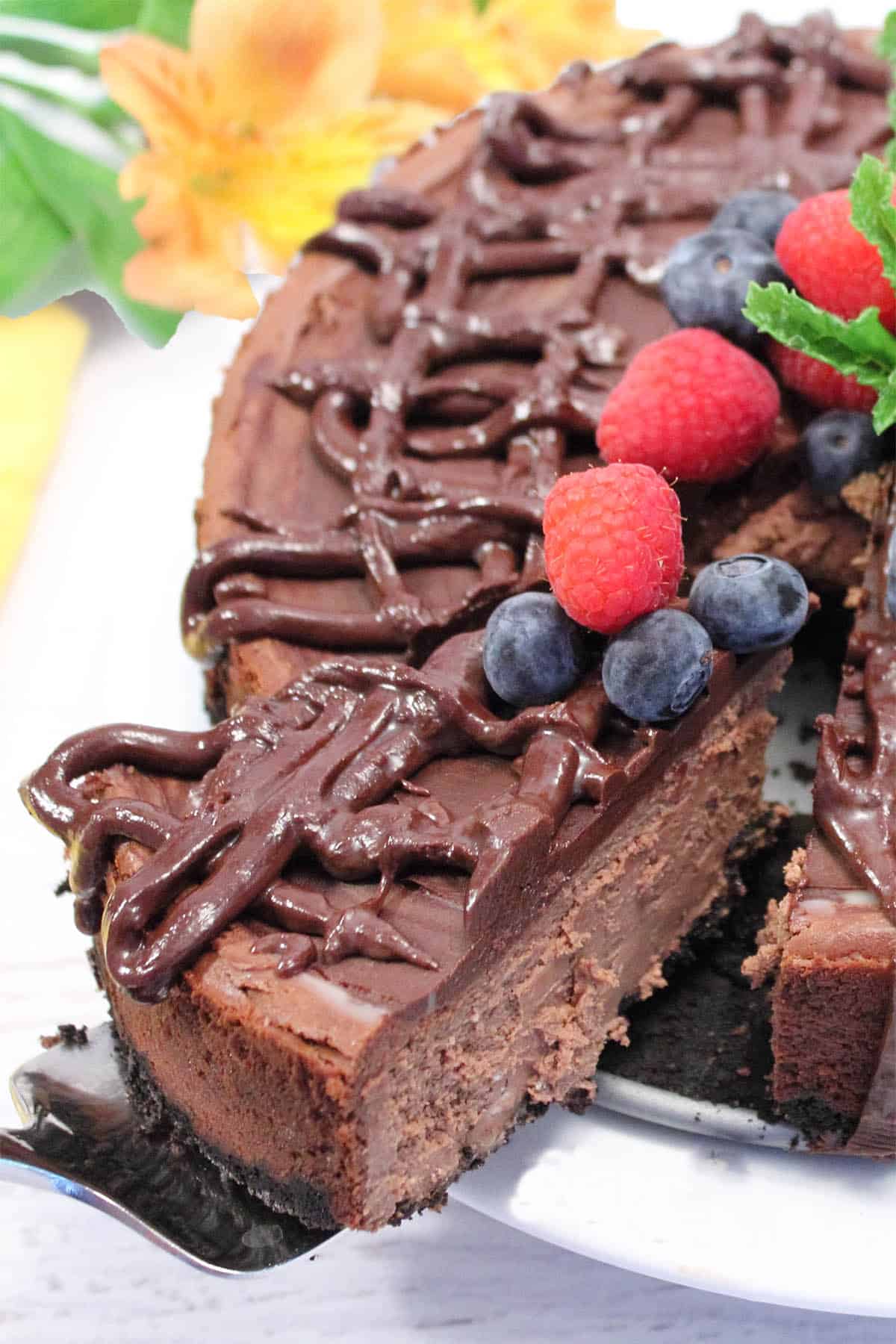 Slice with berry garnish being lifted from cake