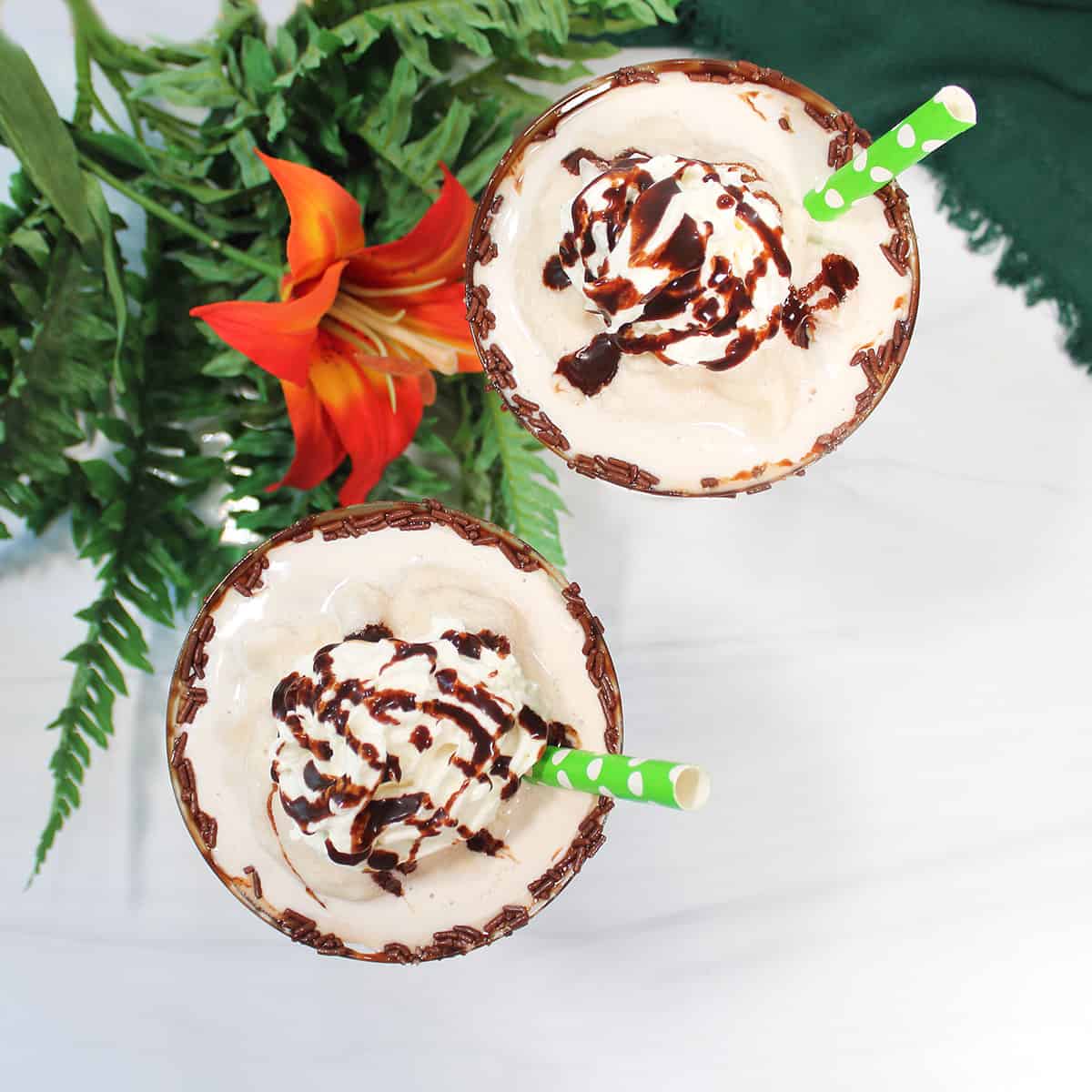 Overhead of two cocktails with green straws.