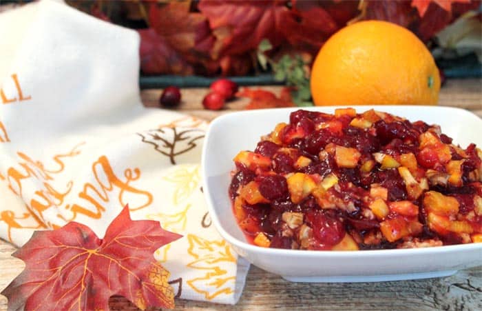 Cranberry Orange Relish in white bowl next to fall towel and leaf.
