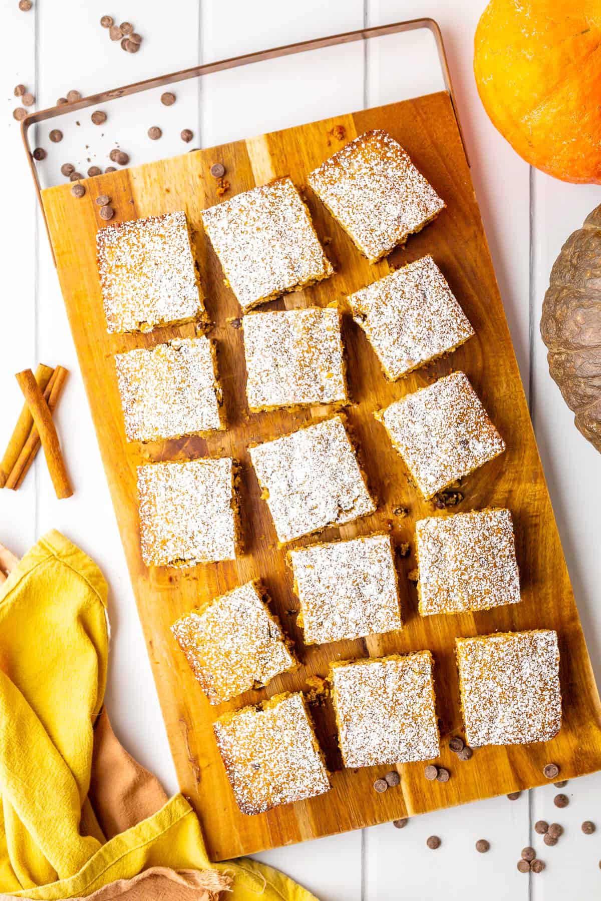 Sliced pumpkin bars on wooden board.
