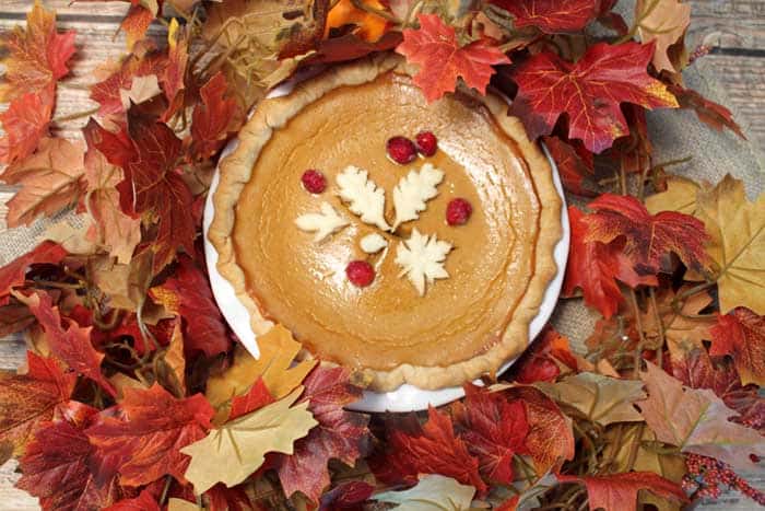 Overhead of Easy Pumpkin Pie with decorations set amongst fall leaves.