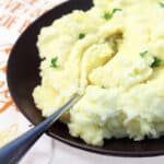 Spoon in a bowl of mashed potatoes.