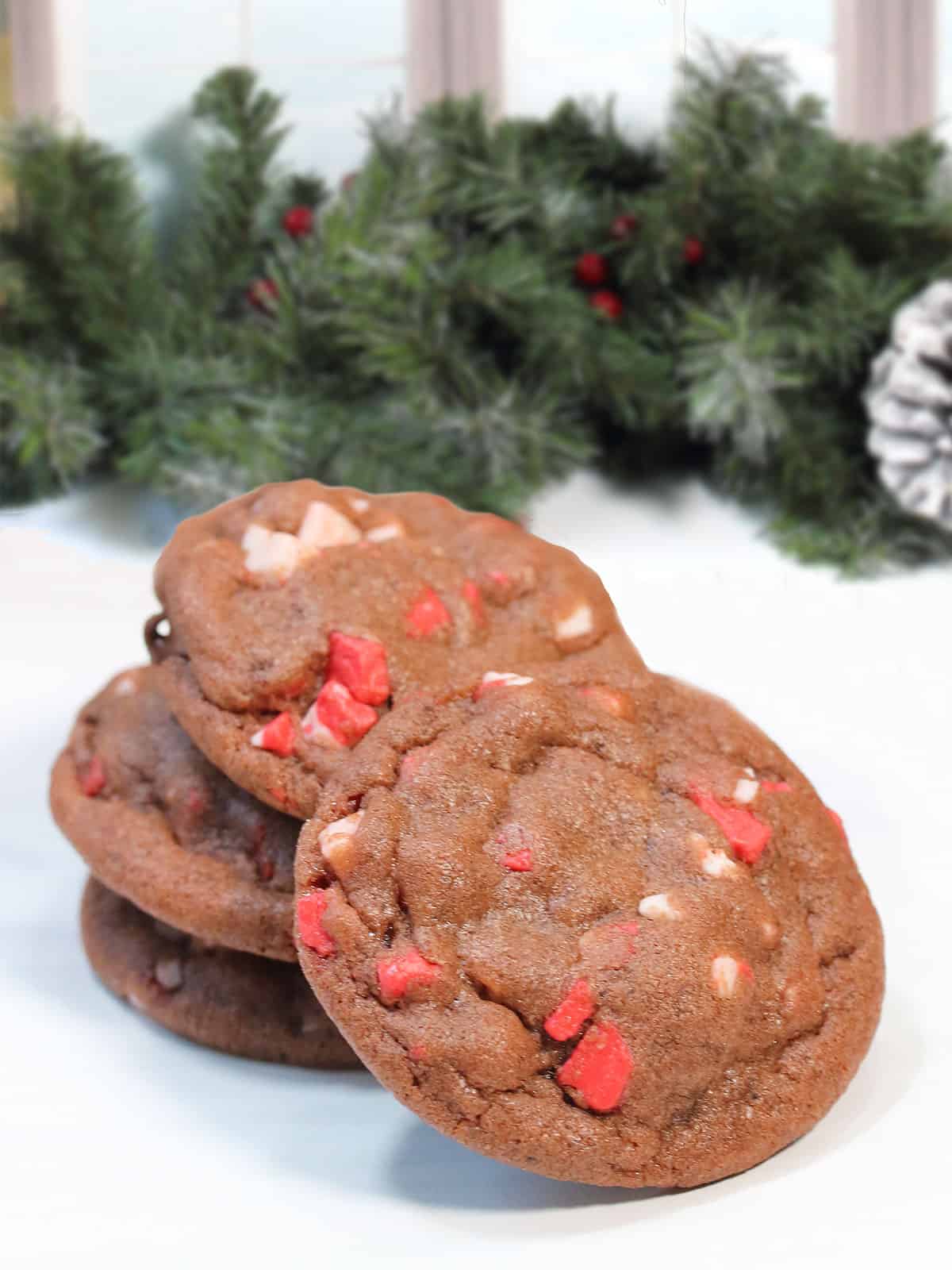 Chocolate Chip Peppermint Chip Cookies stacked by greenery.