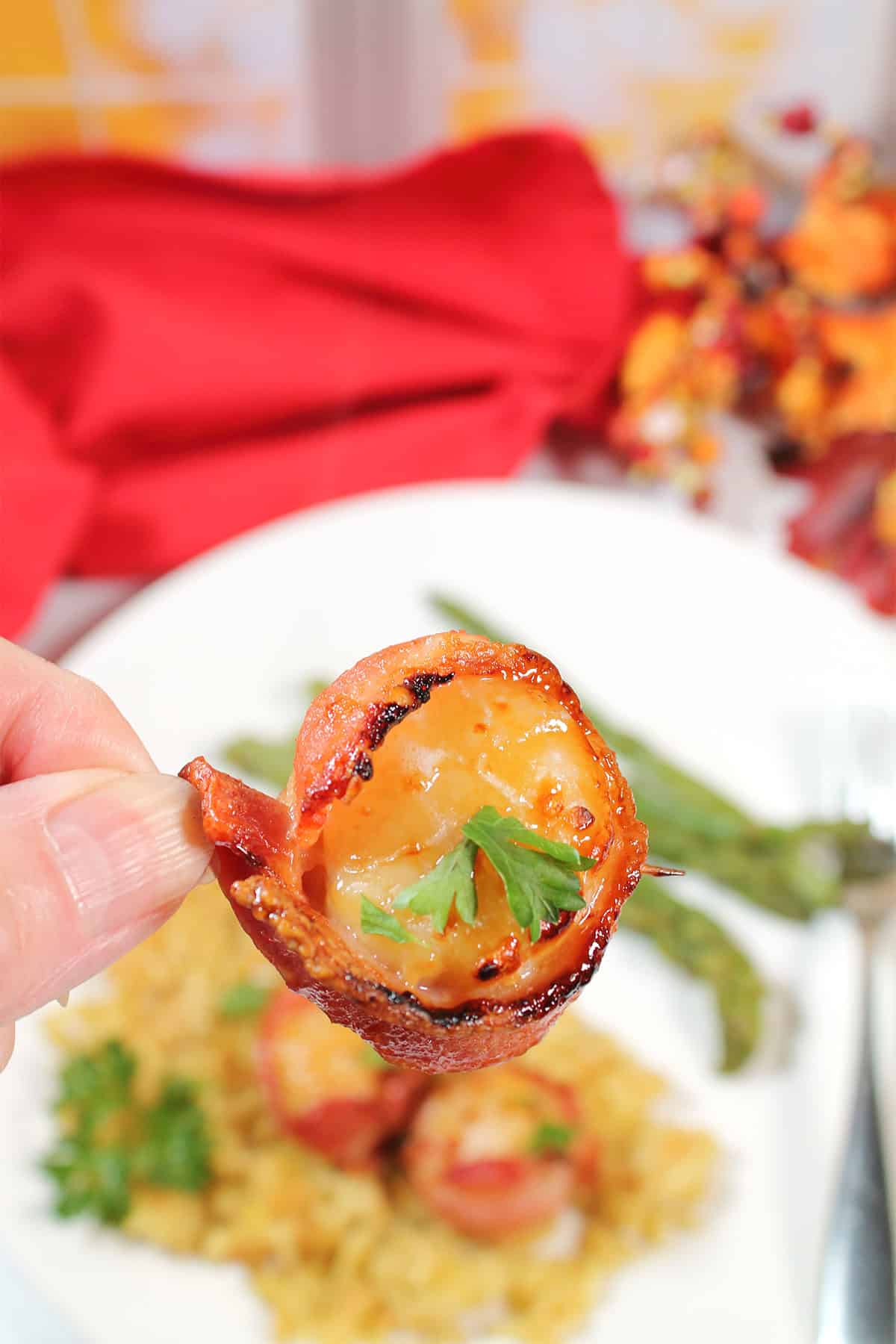 Holding bacon wrapped scallop.