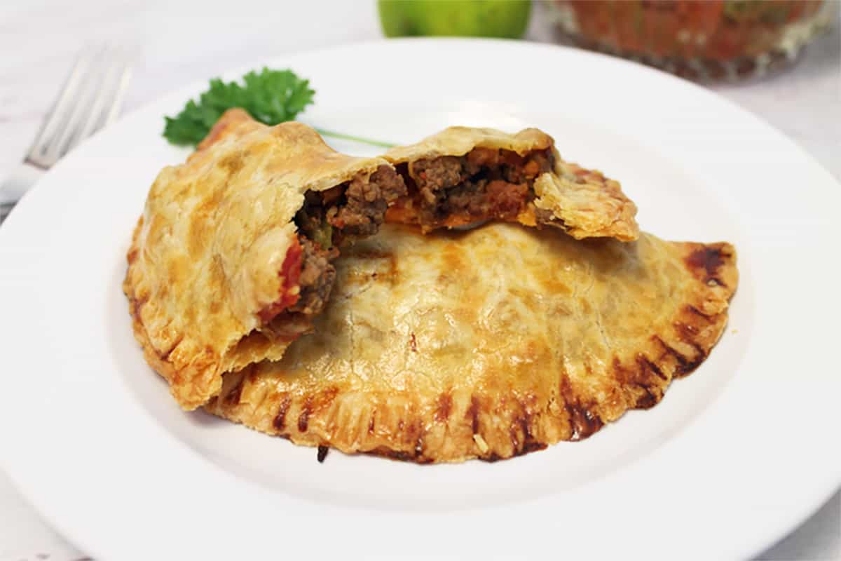 Empanada on white plate with bite taken out.