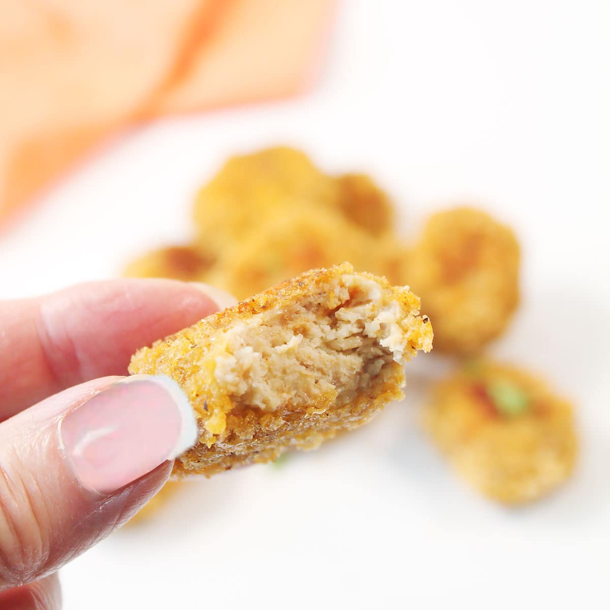 Holding a chicken nugget with bite out of it.