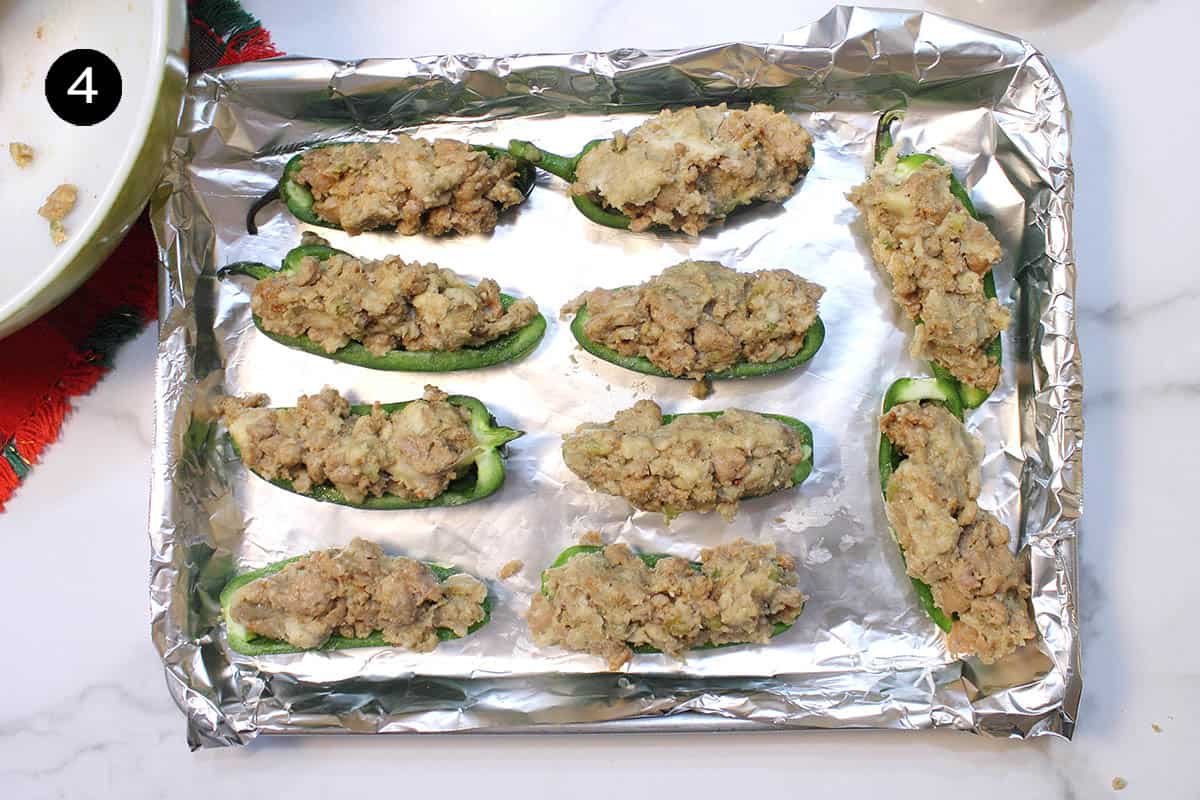 Jalapenos with stuffing in them on cookie sheet.