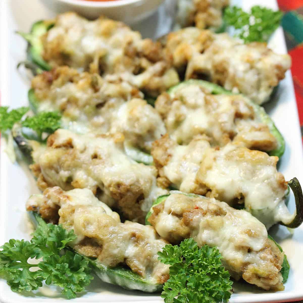 Plateful of jalapeno poppers with sausage and a marinara dipping sauce.