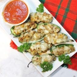 White platter with stuffed jalapenos with marinara on plaid placemat.