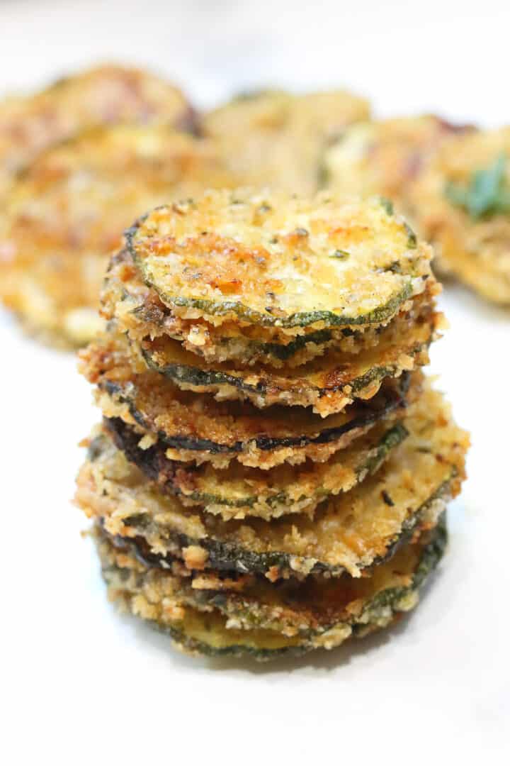 Stack of zucchini chips on white table.