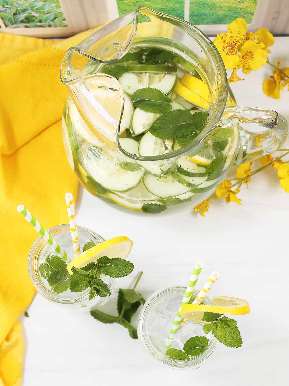 Overhead of pitcher of cucumber lemon water and two mason jar servings.