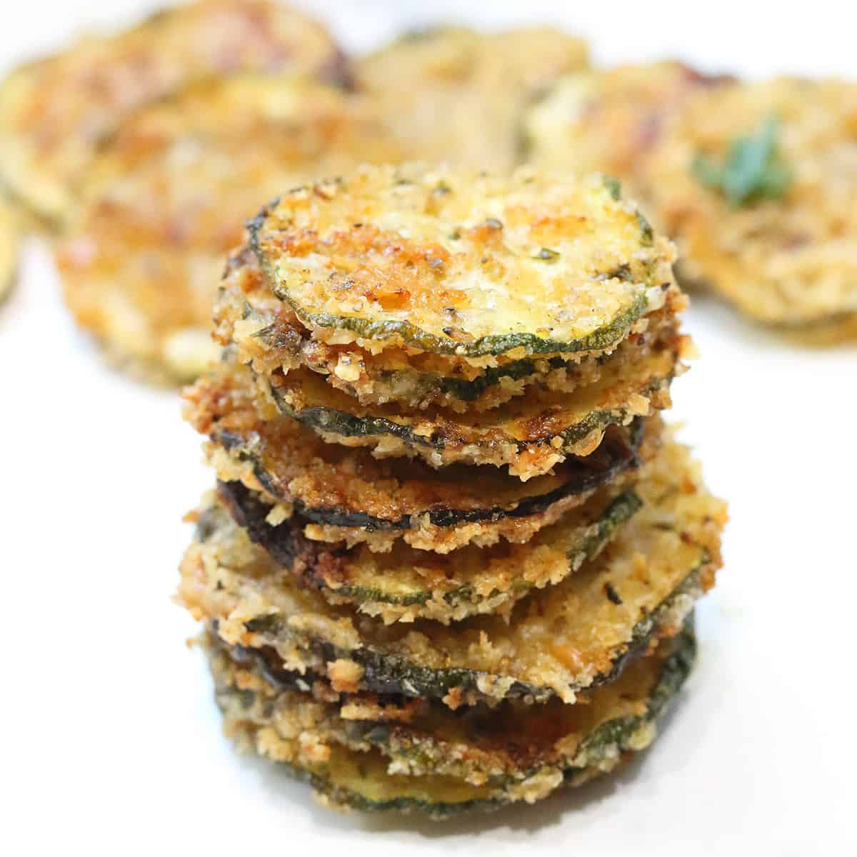 Stack of zucchini chips with more in back.