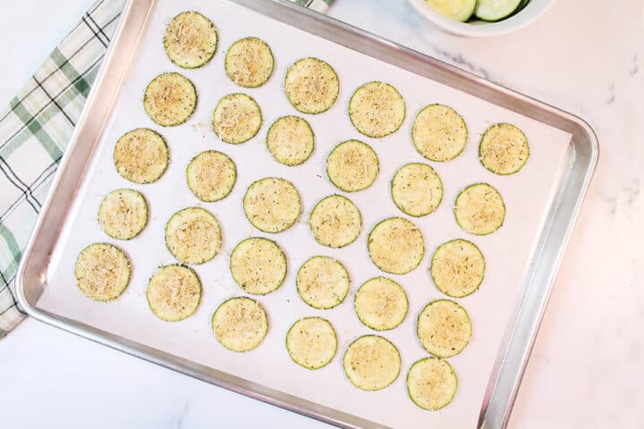Zucchini slices on parchment lined cookie sheet ready to bake.