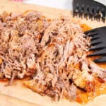 Closeup of pulled pork on wooden board.