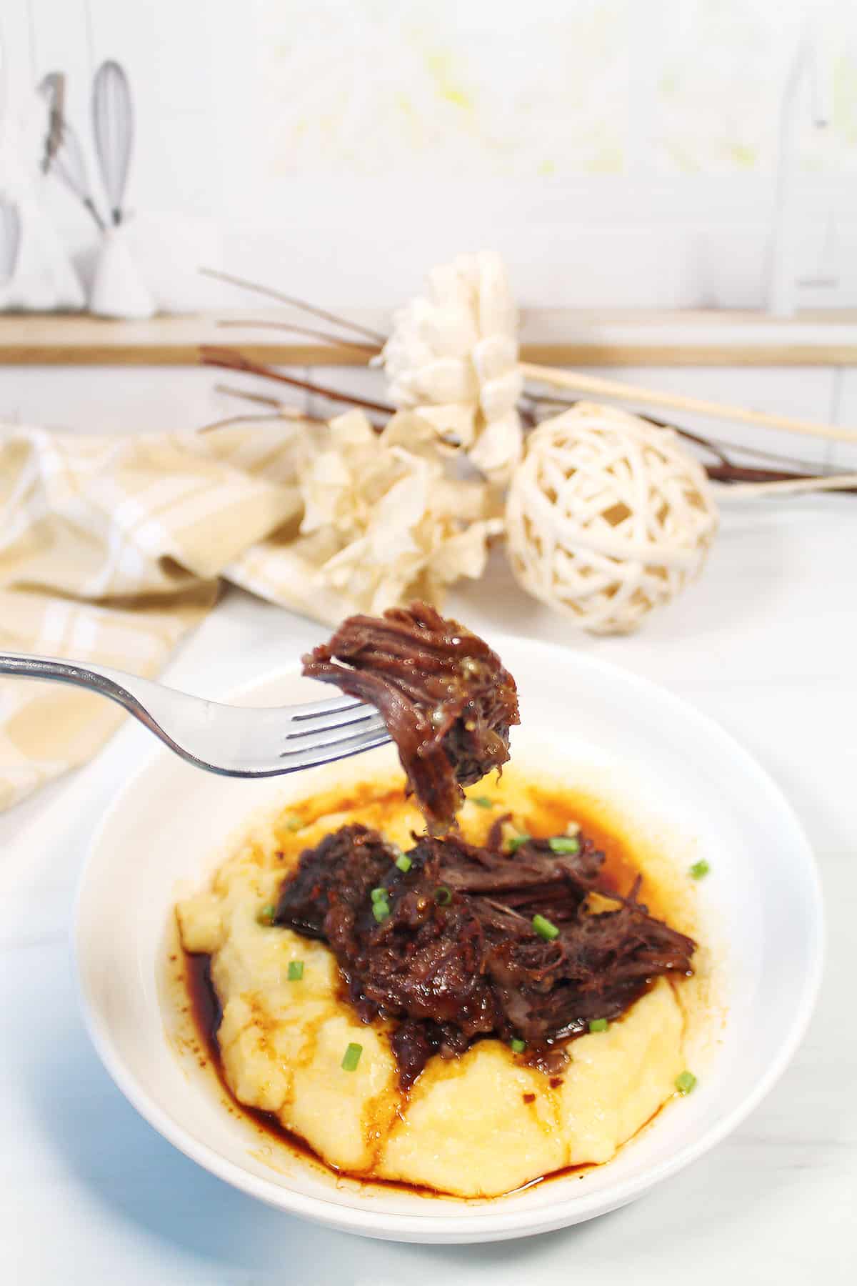 A bite of Hawaiian short ribs served over cheesy polenta.