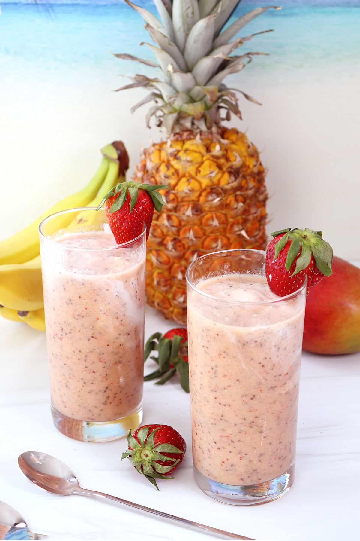 2 Tropical Fruit Smoothies with chia seeds with strawberry garnish.