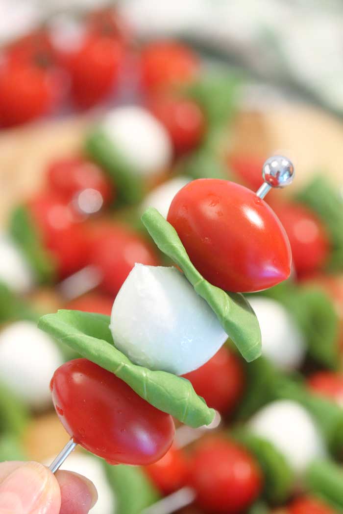 closeup of skewer with tomatoes mozzarella and basil.