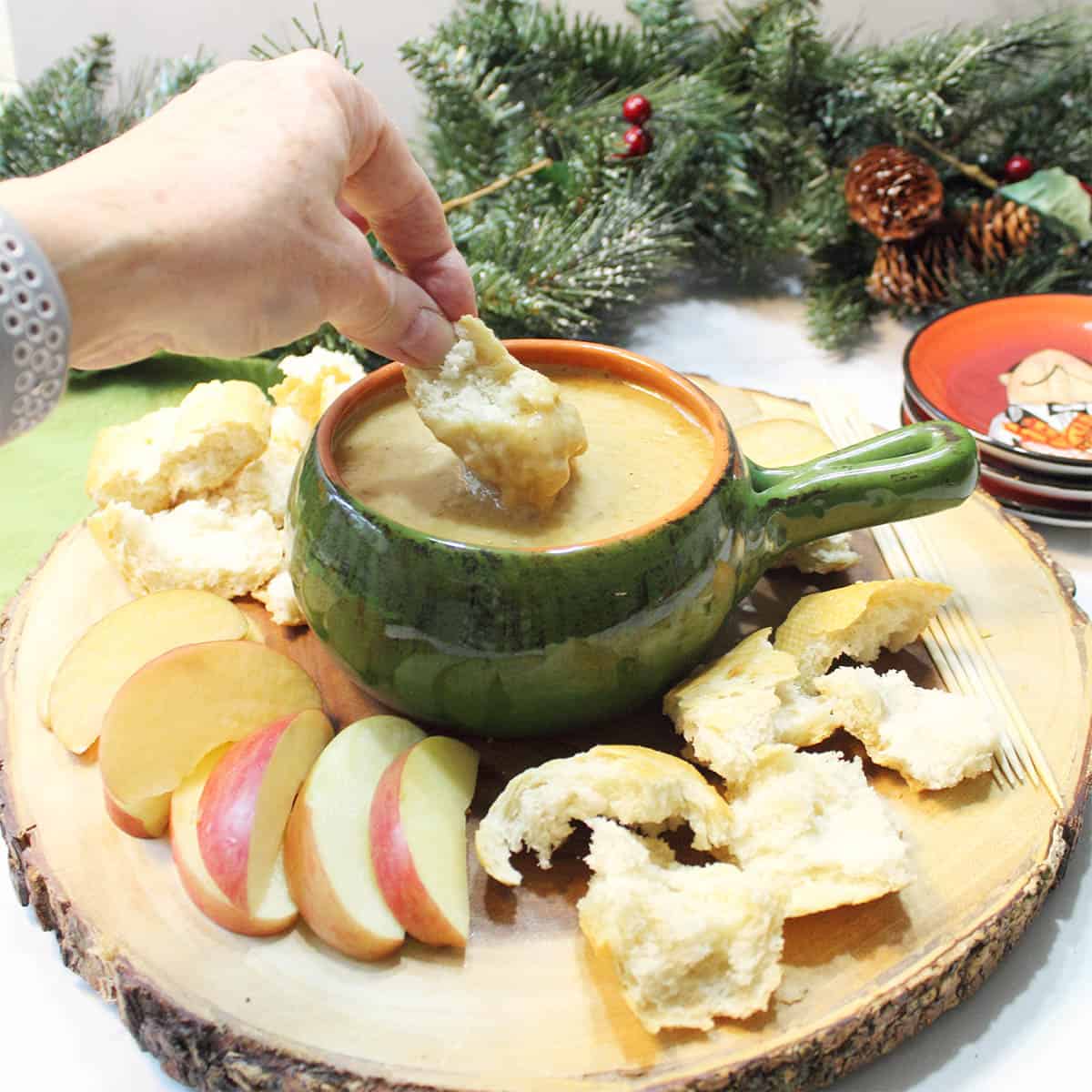 Dipping bread into Melting Pot Cheddar Cheese Fondue fondue surrounded by dippers.