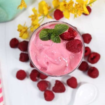 Looking down into glass with raspberry smoothie and berry mint garnish.
