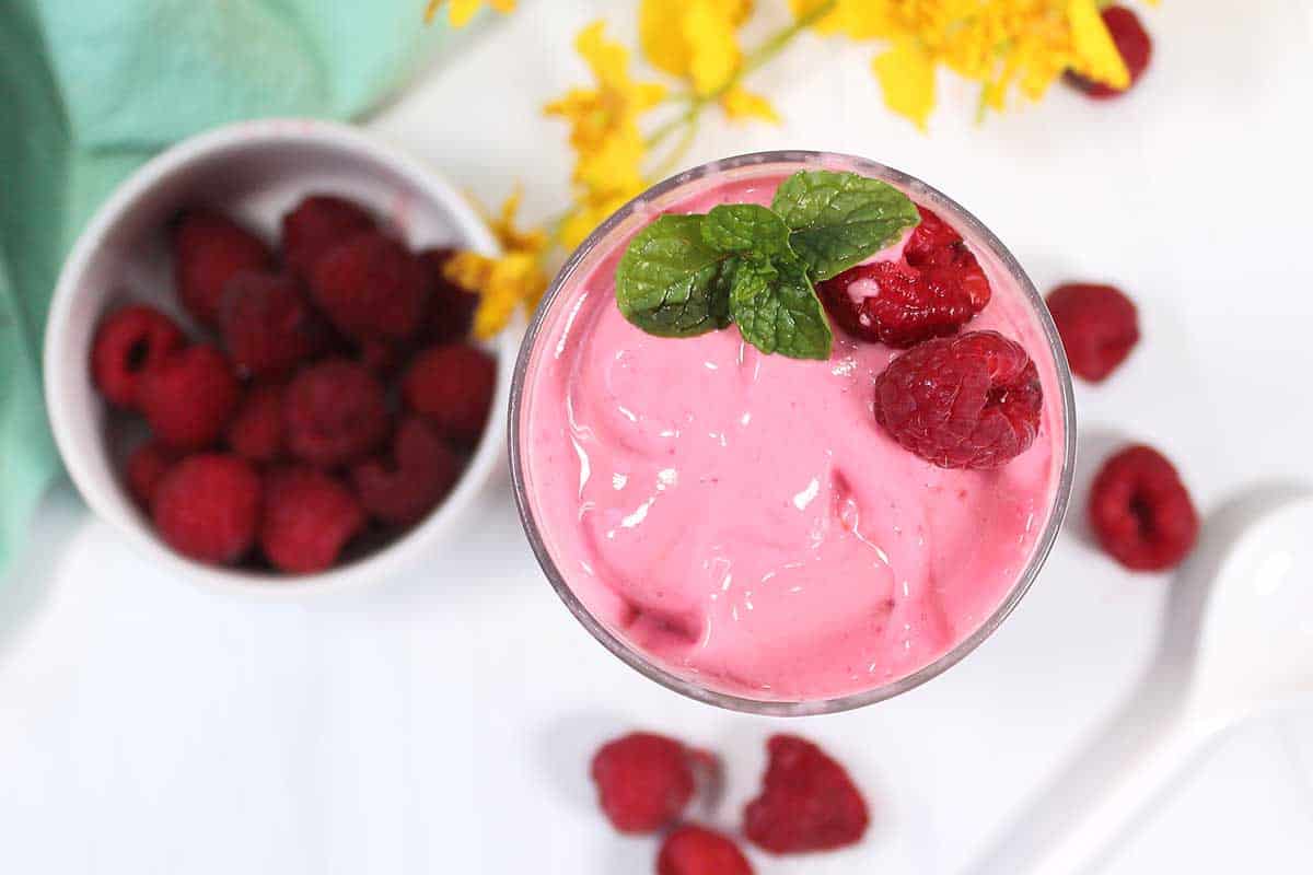 Overhead of smoothie with raspberry and mint garnish.