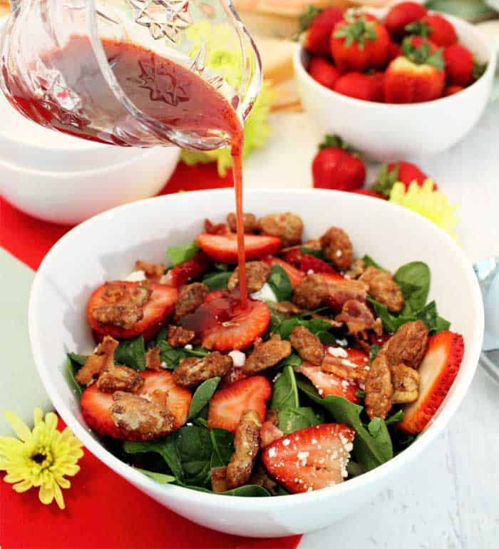 Drizzling vinaigrette on Spinach Strawberry Salad with Goat Cheese