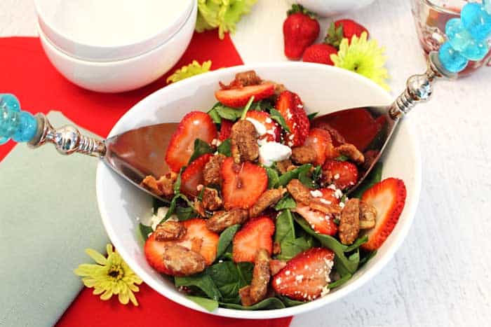 Tossing Spinach Strawberry Salad in white bowl