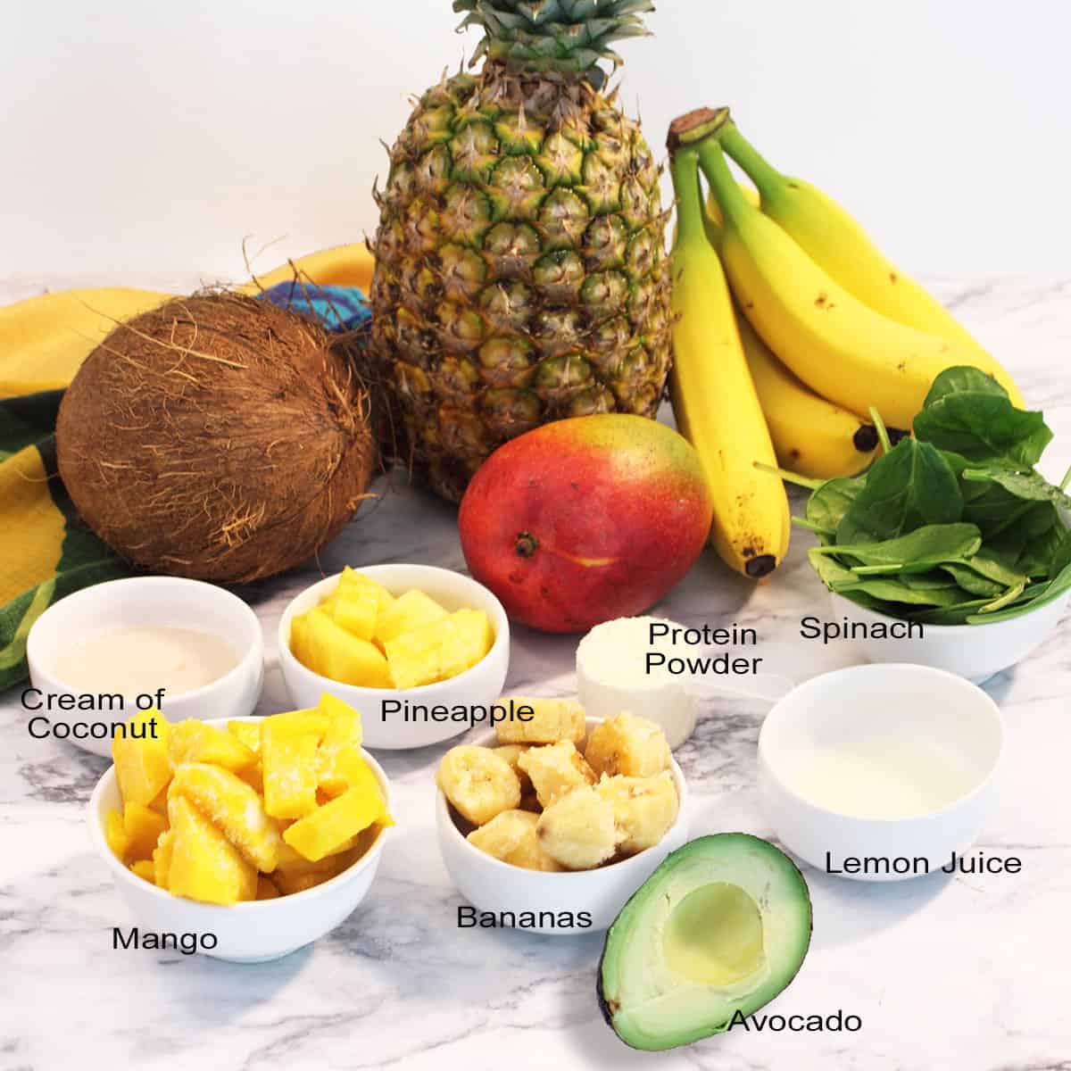 Green pina colada smoothie ingredients on marble table.