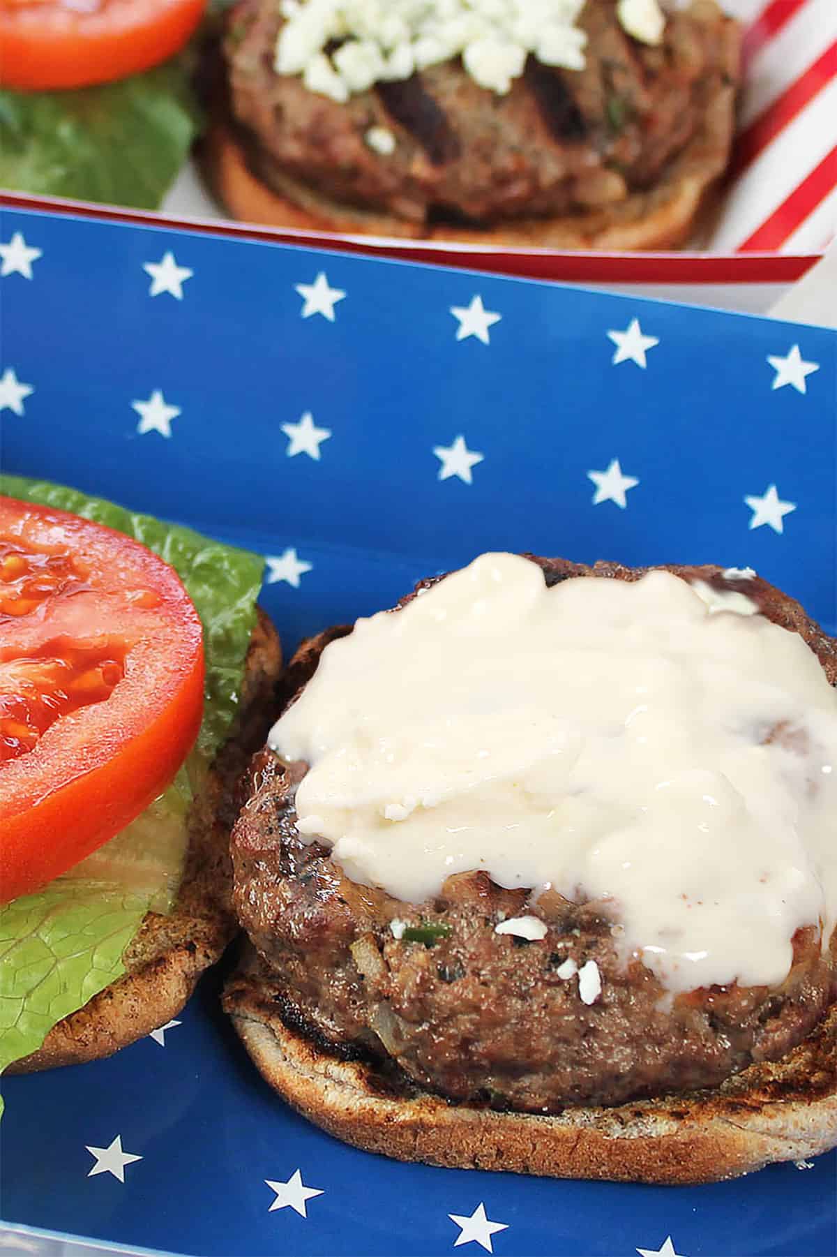 Closeup of burgers with blue cheese melted on top.