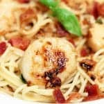 Closeup of scallop with bacon on top of pasta