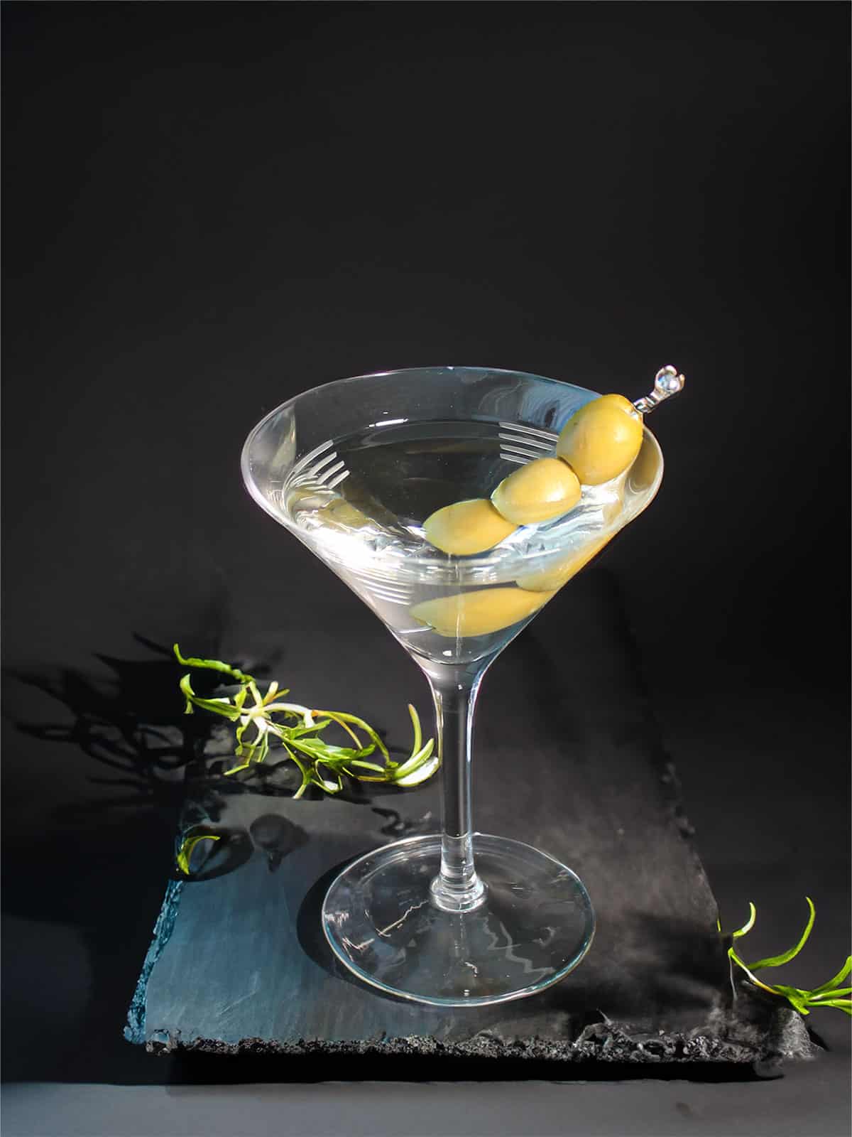 Classic dry martini with olives on slate.