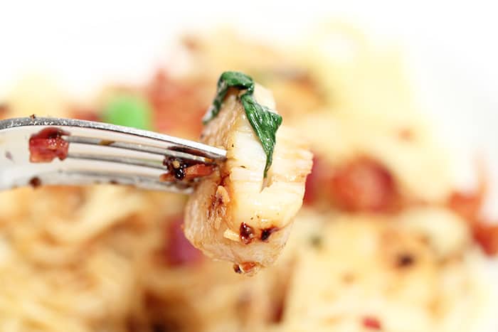 bite of cooked scallop showing basil inside