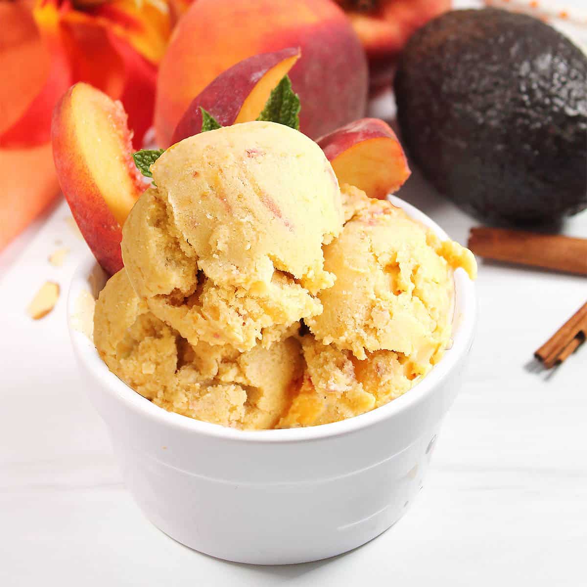 Healthy peach ice cream in dish with sliced peaches.