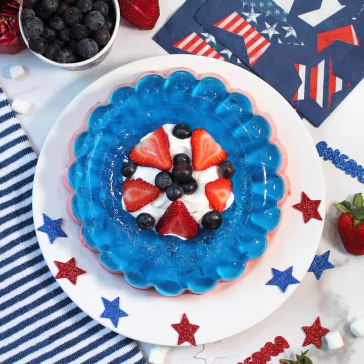 Overhead of red white and blue jello salad with patriotic napkins and blueberries.
